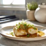 Photorealistic image of Japanese Simmered Fish (Sakana no Nitsuke) plated with soy-mirin glaze and ginger garnish in a modern kitchen under natural light.