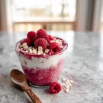Raspberry Chia Pudding served in a glass jar with fresh raspberries and granola
