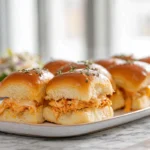 freshly baked buffalo chicken sliders on a plate with melted cheese and buttery glaze