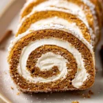beautifully sliced fall pumpkin spice roll cake with cream cheese filling on white plate in modern kitchen