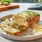 garlic parmesan chicken meatloaf plated with parmesan crust and fresh herbs in bright modern kitchen