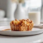 Photorealistic oatmeal apple breakfast bake on a plate with golden oats, diced apples, and maple drizzle in a modern kitchen setting.