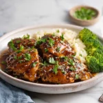 Slow cooker chicken thighs plated with sauce and parsley garnish in modern kitchen