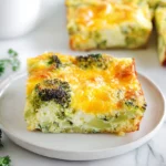 Broccoli Cheddar Egg Bake plated on a white dish with melted cheese and broccoli in a modern kitchen