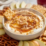 Photorealistic bowl of caramel apple cheesecake dip with caramel drizzle and apple slices on a modern kitchen counter