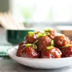 Sweet Chili Meatballs Crockpot plated dish with garnishes, natural daylight, shallow depth of field.