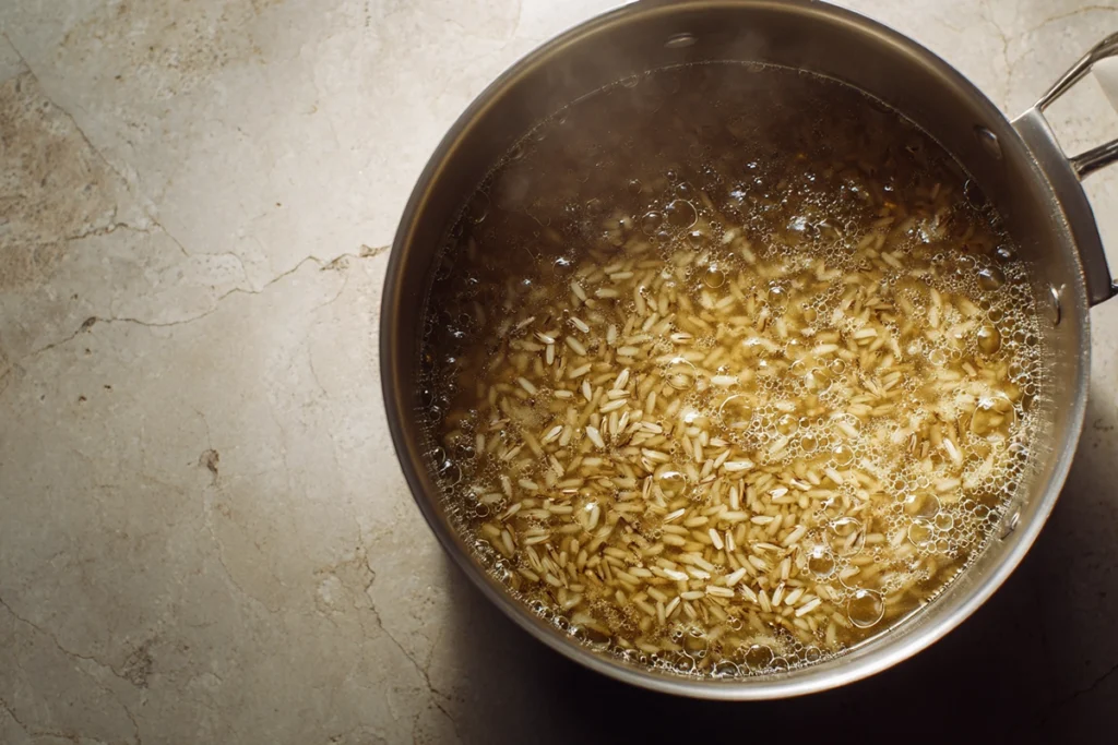 Wild rice simmering in broth for creamy mushroom chicken wild rice soup