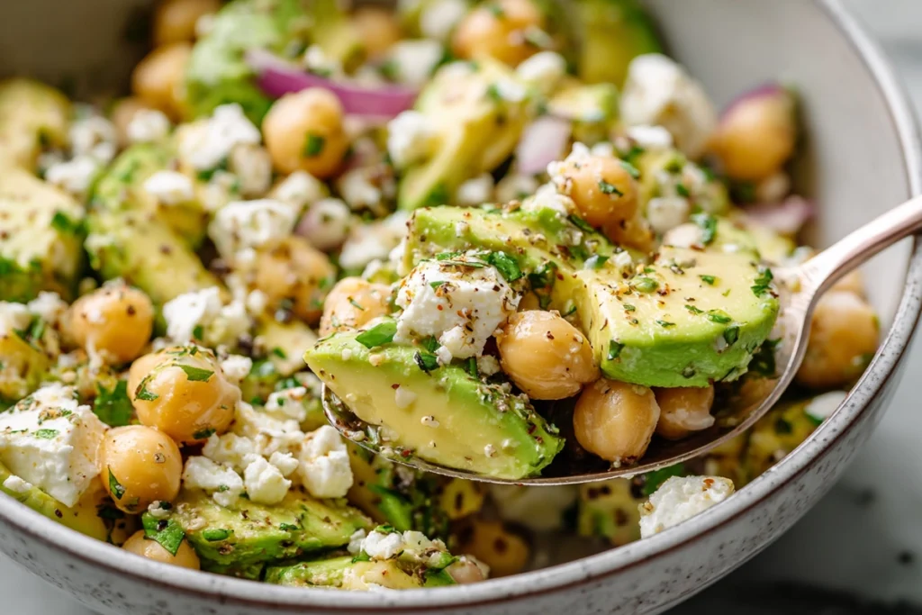 Serving spoon lifting Chickpea Feta Avocado Salad before eating