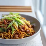 Sticky beef noodles served on a modern plate with glossy sauce and tender beef