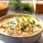 Creamy white chicken chili served in a bowl with chicken, beans, and fresh toppings in a bright home kitchen