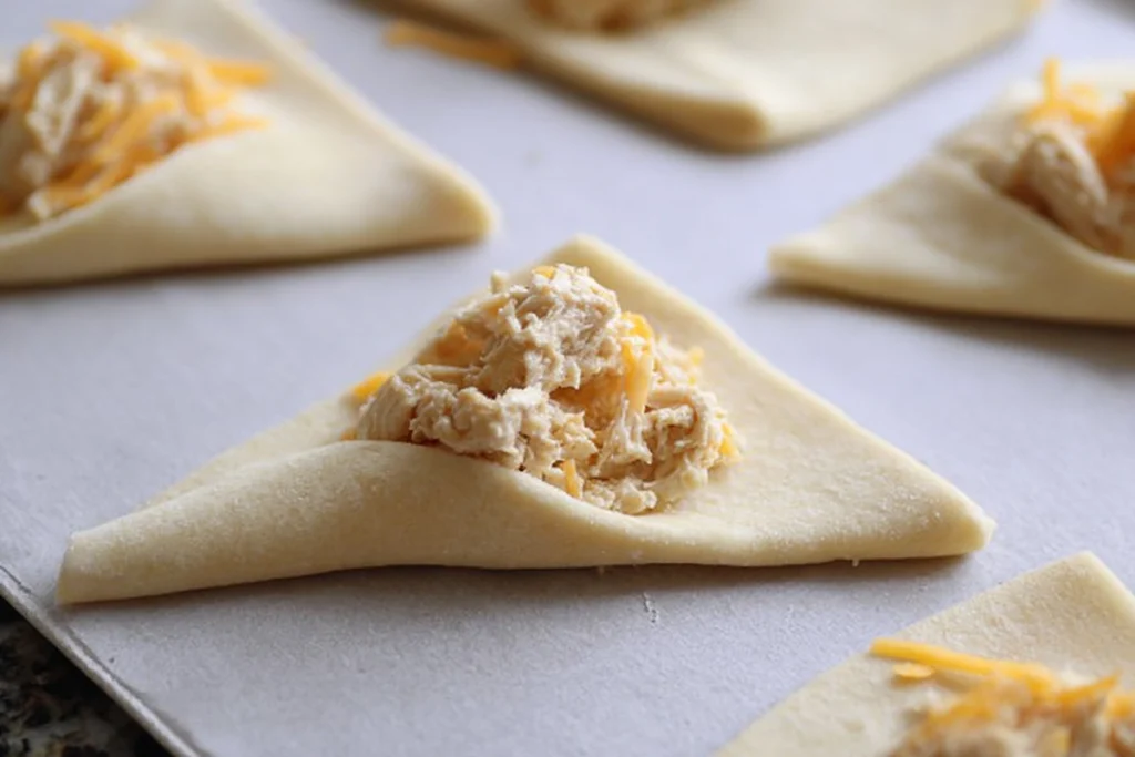Filling and rolling crescent dough for Cheesy Chicken Crescent Bake before baking