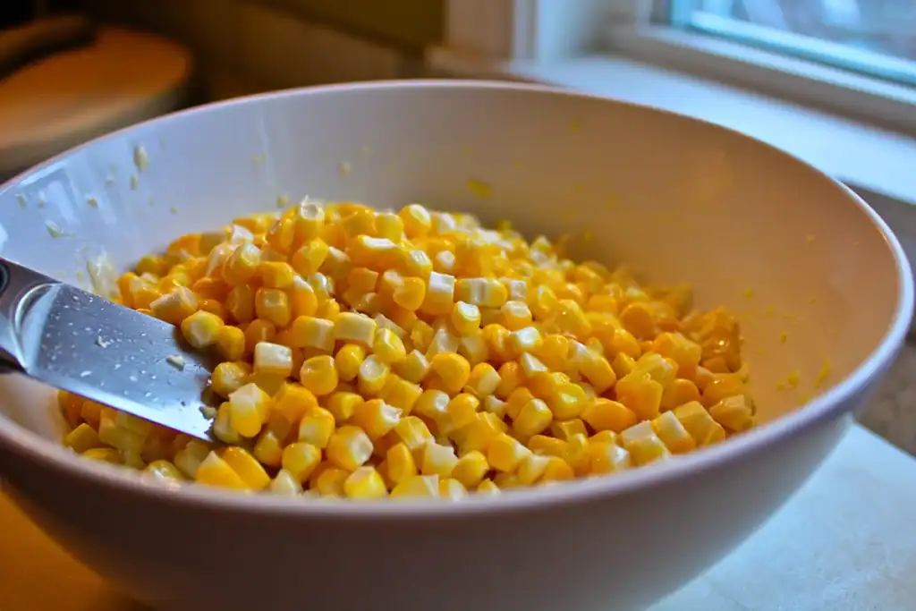 Cutting fresh corn kernels for Creamy Corn Salad with visible corn milk