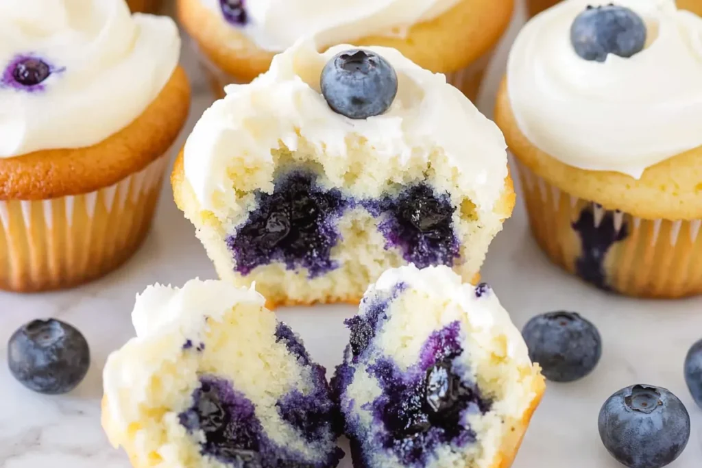 Lemon blueberry cupcakes with a bite taken out showing blueberry-filled crumb and frosting