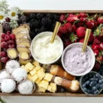 Chef Taha Ayad's Recipe Summer Dessert Board with berries, cakes, creamy dips, and chamomile flowers