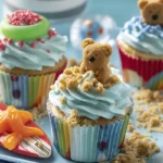 Teddy-at-the-Beach Cupcakes decorated with blue frosting, teddy grahams, gummy rings, fruit snack strips, and graham cracker sand