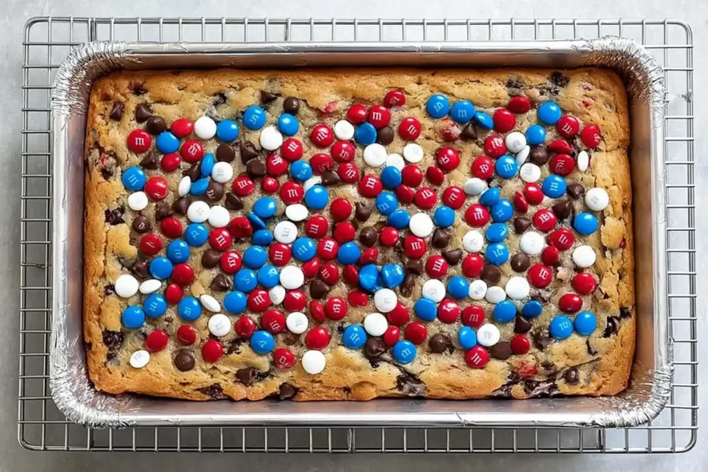 4th of July Cookie Bars That Feed a Crowd Without Fuss 10 Baked 4th of July cookie bars in a foil lined pan with golden edges and colorful M&M's