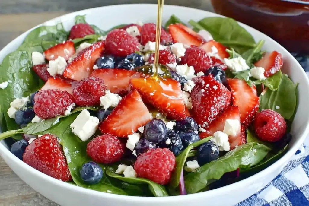 Spinach berry salad with homemade poppyseed dressing drizzled over fresh berries and feta