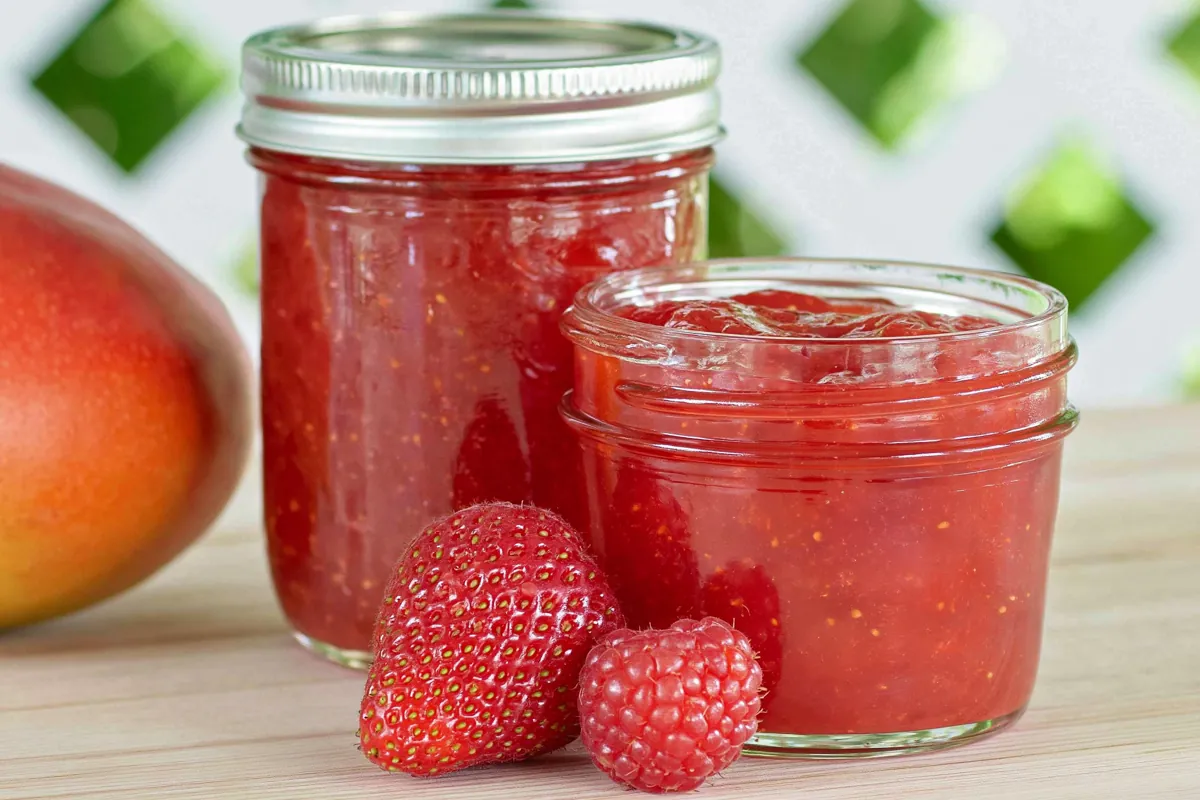 Chef Taha Ayad's Recipe Strawberry Mango Jam in stacked jars with fresh mango and strawberries