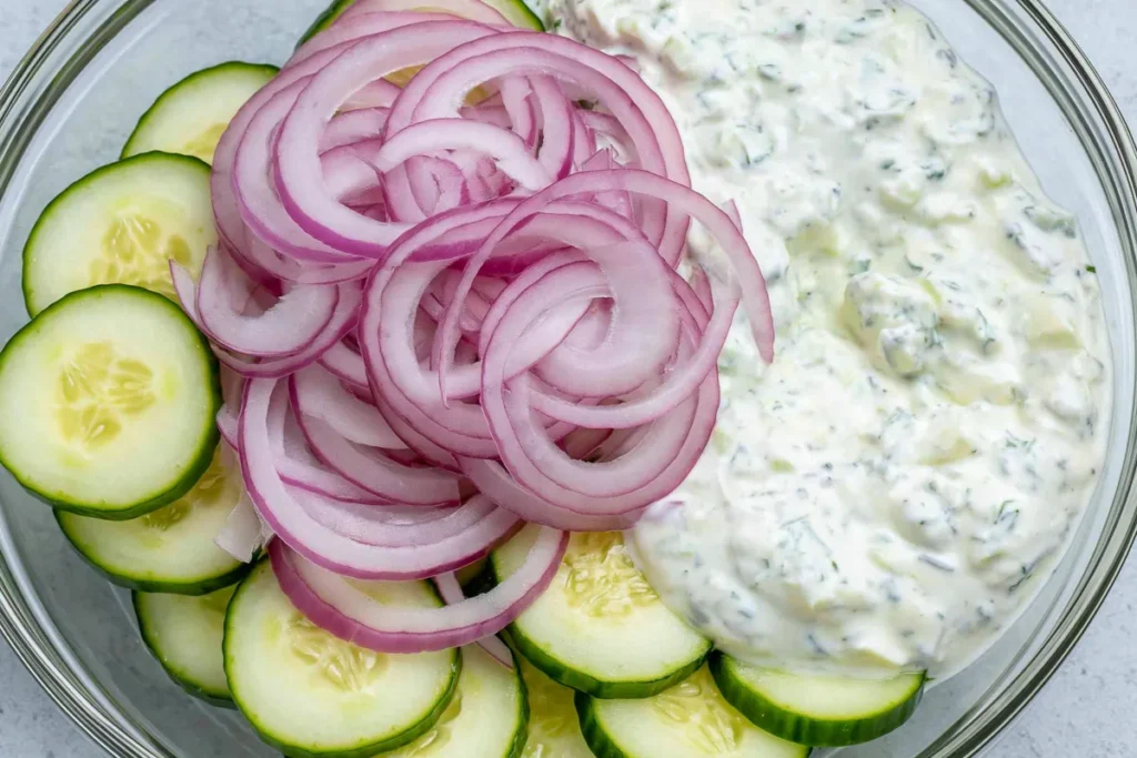 Tzatziki Cucumber Salad before tossing with sliced cucumber, red onion, and creamy herb Greek yogurt dressing