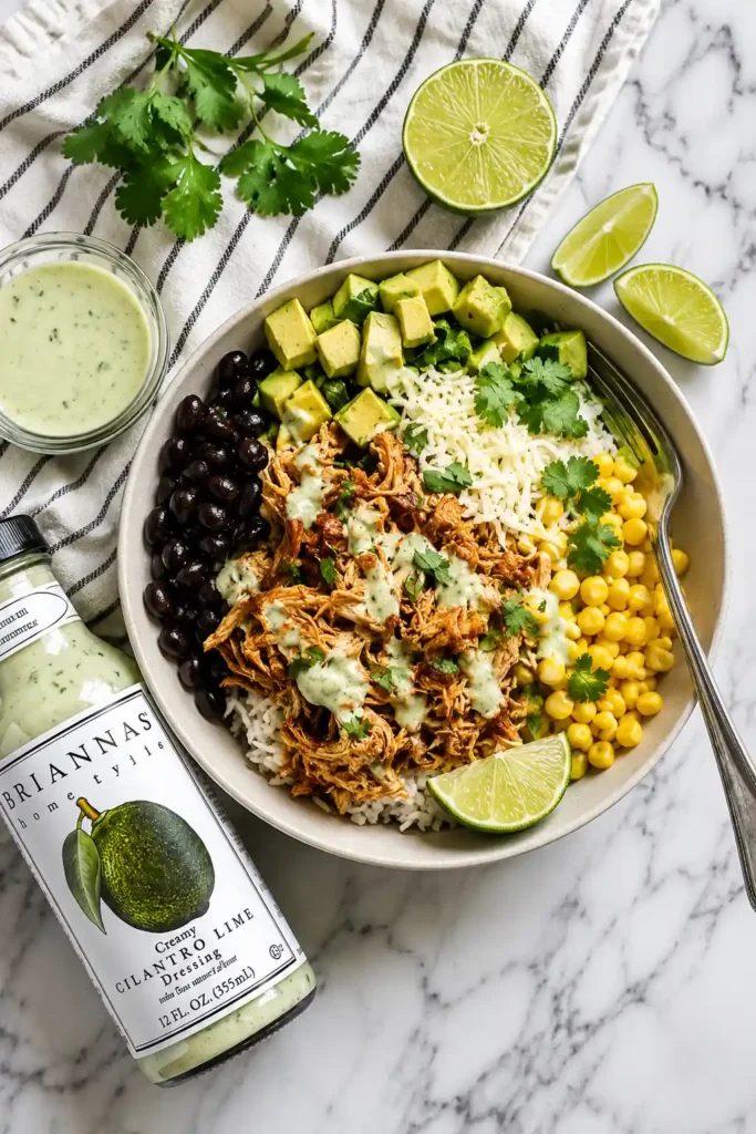 Slow Cooker Chicken Burrito Bowl for an Easy Family Dinner 5 Assembled Slow Cooker Chicken Burrito Bowl with rice, shredded chicken, beans, corn, avocado, cilantro, lime, and dressing