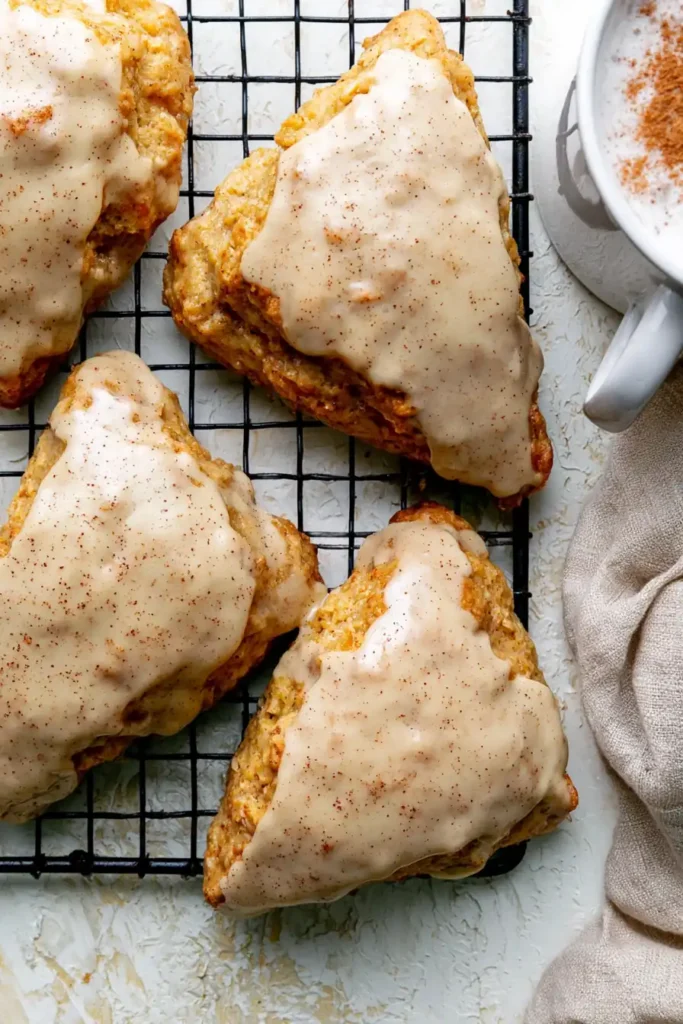 Homemade Chai Scones with a Thick Maple Chai Glaze 9 Homemade Chai Scones Stacked on a Cooling Rack Beside Hot Tea