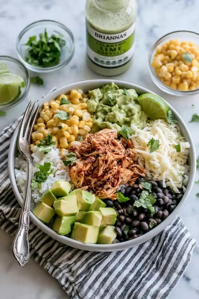 Slow Cooker Chicken Burrito Bowl for an Easy Family Dinner 3 Slow Cooker Chicken Burrito Bowl ingredients with seasoned chicken, rice, black beans, corn, avocado, cilantro, lime, and dressing